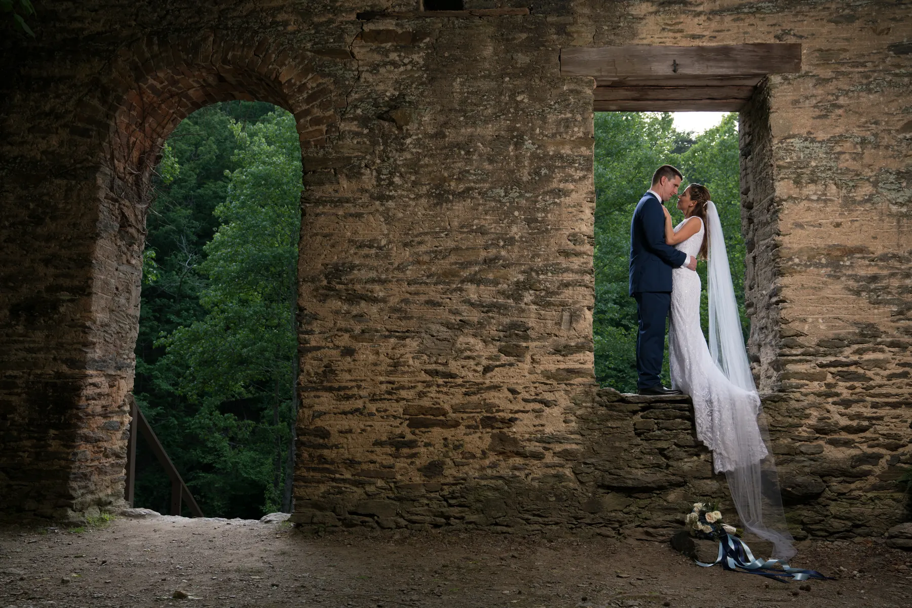 Bride and groom embracing inside the stone ruins of an old mill near Atlanta, veil catching the light